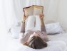 woman-lying-white-bed-reading-book-home